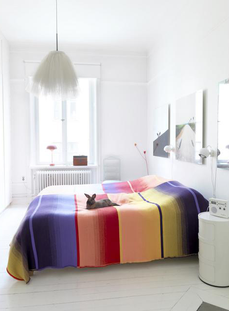 baltas miegamasis su spalvota antklode ant lovos