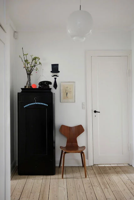 juoda spinta, medinė kėdė, baltos durys, siena