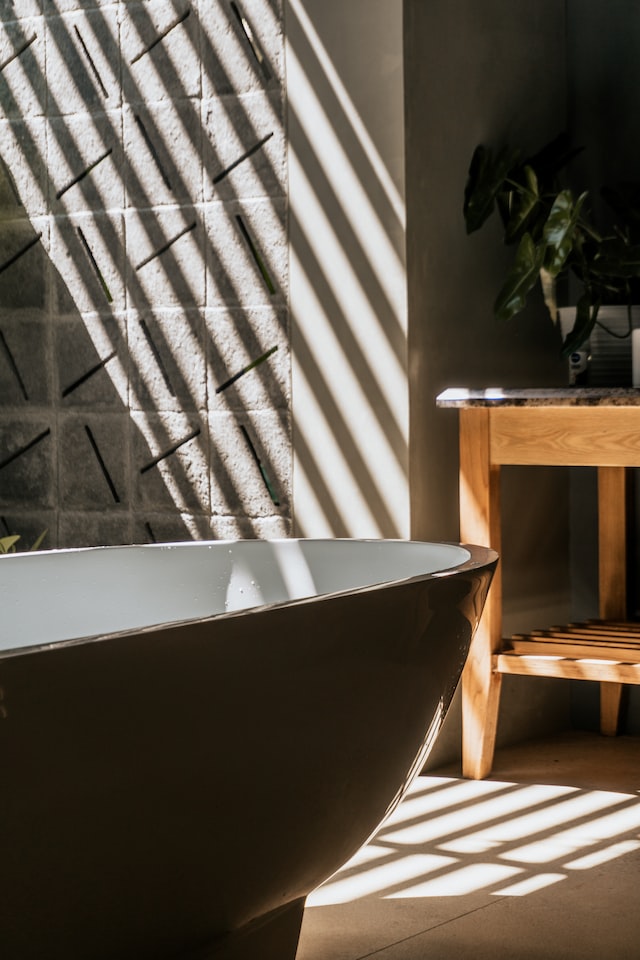 vonia, medinis stalas, saulės šviesa krinta ant sienos